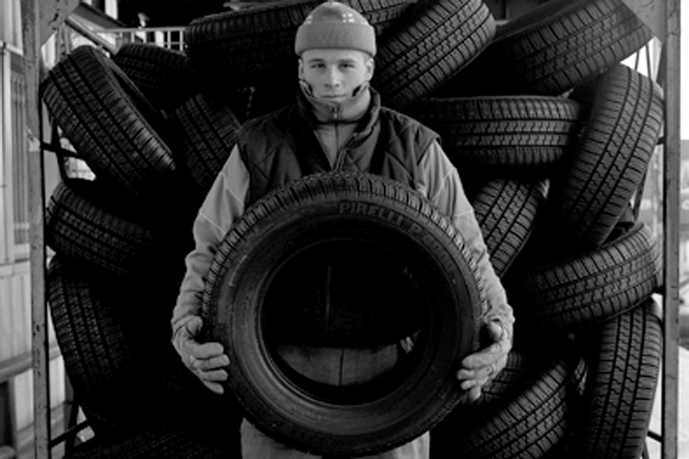 Homme devant un tas de pneus